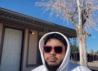 a man wearing sunglasses in front of a house