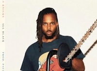 a man with dreadlocks holding a chainsaw