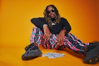 a man with dreadlocks sitting on the ground with money